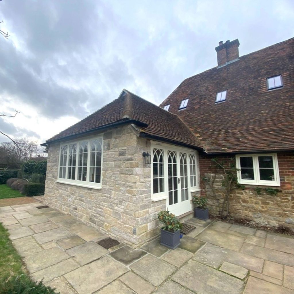 New timber framed extenson constructed in ragstone with painted timber fenestration and half-hipped end roof.